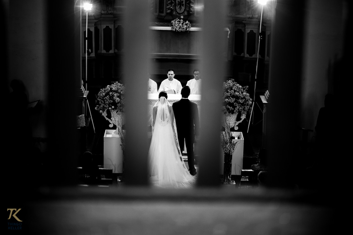 Fotografia de Casamento de Maura e Thiago realizado na cidade de Paracatu, Minas Gerais.  Detalhe do casal no altar da Igreja do Rosário. Foto em preto e branco.