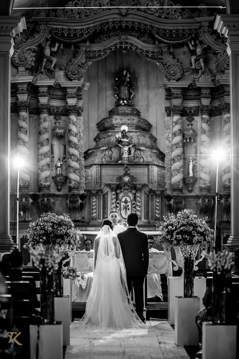 Fotografia de Casamento de Maura e Thiago realizado na cidade de Paracatu, Minas Gerais. Noivos no altar. Foto em preto e branco.