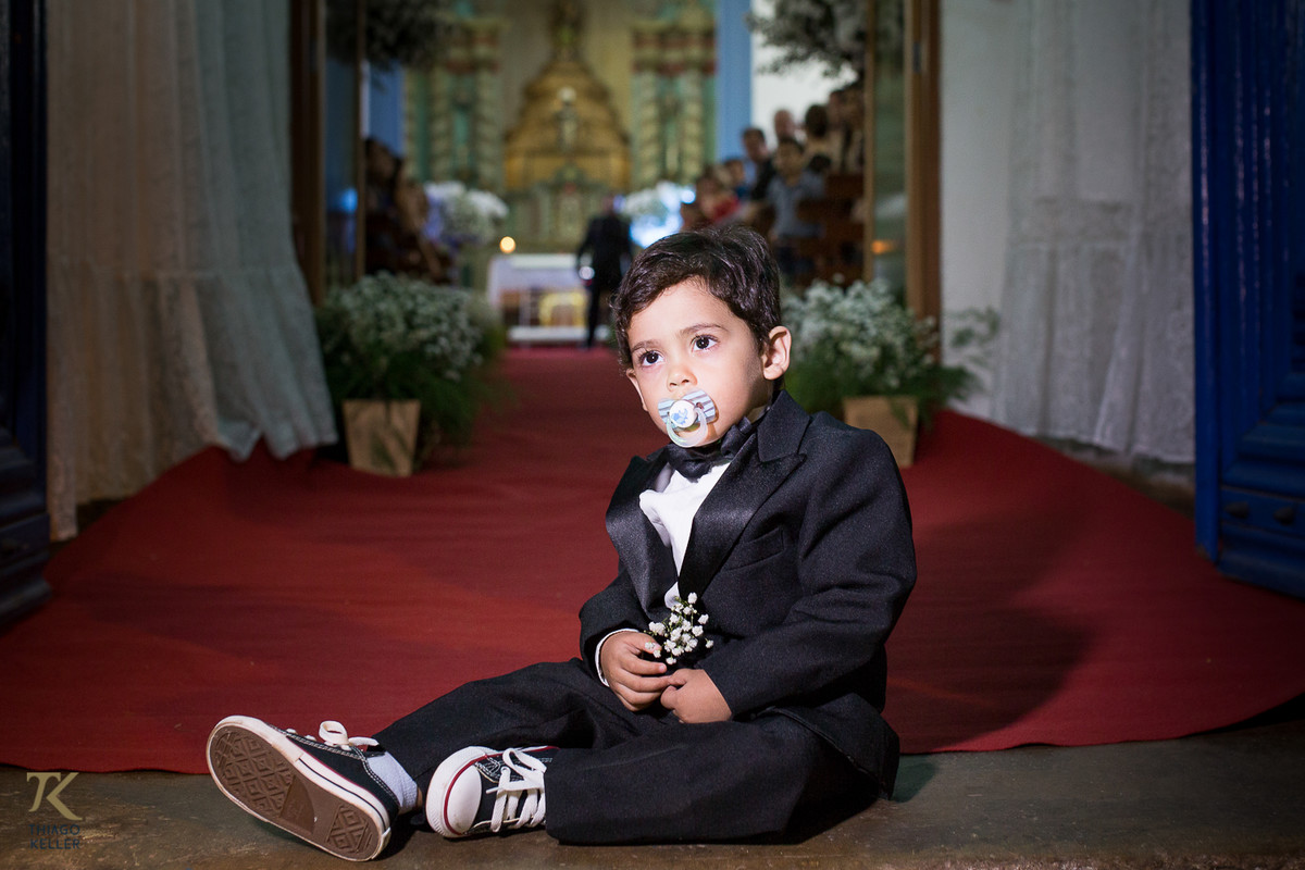 Fotografia de casamento de Ana Rita e Everton. Pajem com bico na frente da Igreja do Rosário em Paracatu.