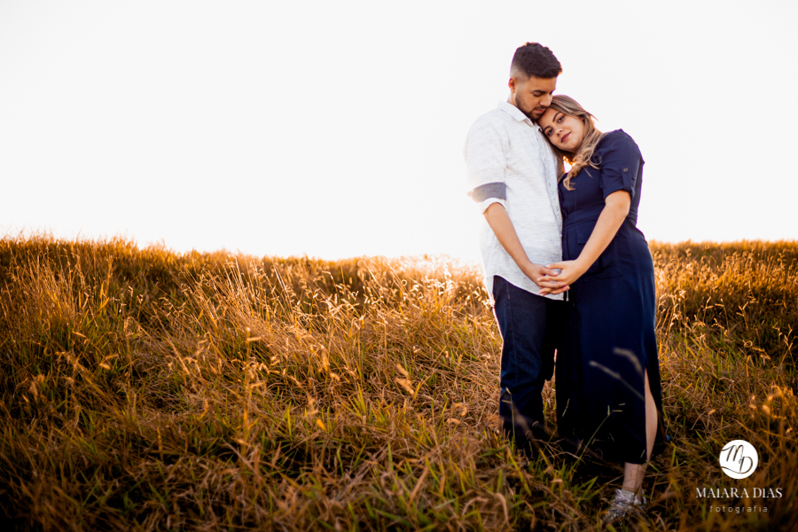 Pré Wedding Vitor e Luiza na cidade de Itirapina no Interior de São Paulo. Ensaio Fotográfico feito no morro do fogão no por do sol. Maiara Dias Fotografia. Noivos dando um abraço com luz de ouro