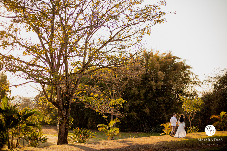 ENSAIO PRE WEDDING SAMIRA E SILAS EM UMA FAZENDA NA CIDADE DE MONTE MOR NO INTERIOR DO ESTADO DE SÃO PAULO, FOTOS FEITAS PELA MAIARA DIAS FOTOGRAFIA, NOIVOS DE BRANCO CAMINHANDO DE MÃOS DADAS NO POR DO SOL