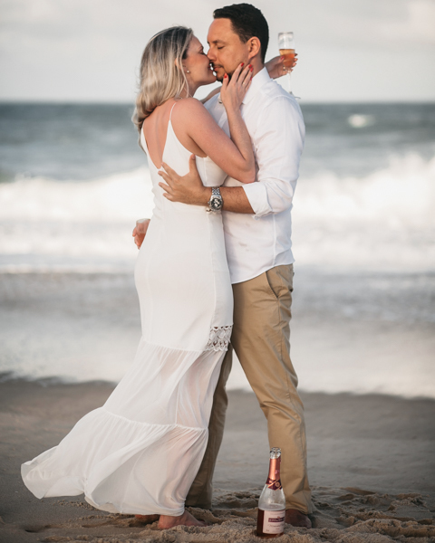 NOIVO COM CAMISA BRANCA E CALÇA BEGE NUM ENSAIO PRE WEDDING NA SESSÃO EXTERNA NO POR DO SOL DA PRAIA DO BEACH PARK EM AQUIRAZ BRINDARAM A FELICIDADE DO CASAL JA PROXIMO DO SEU CASAMENTO
