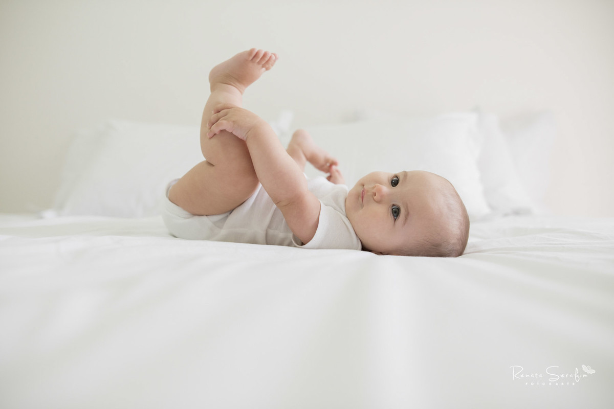 cora linda segurando o pézinho em seu ensaio de acompanhamento de bebê