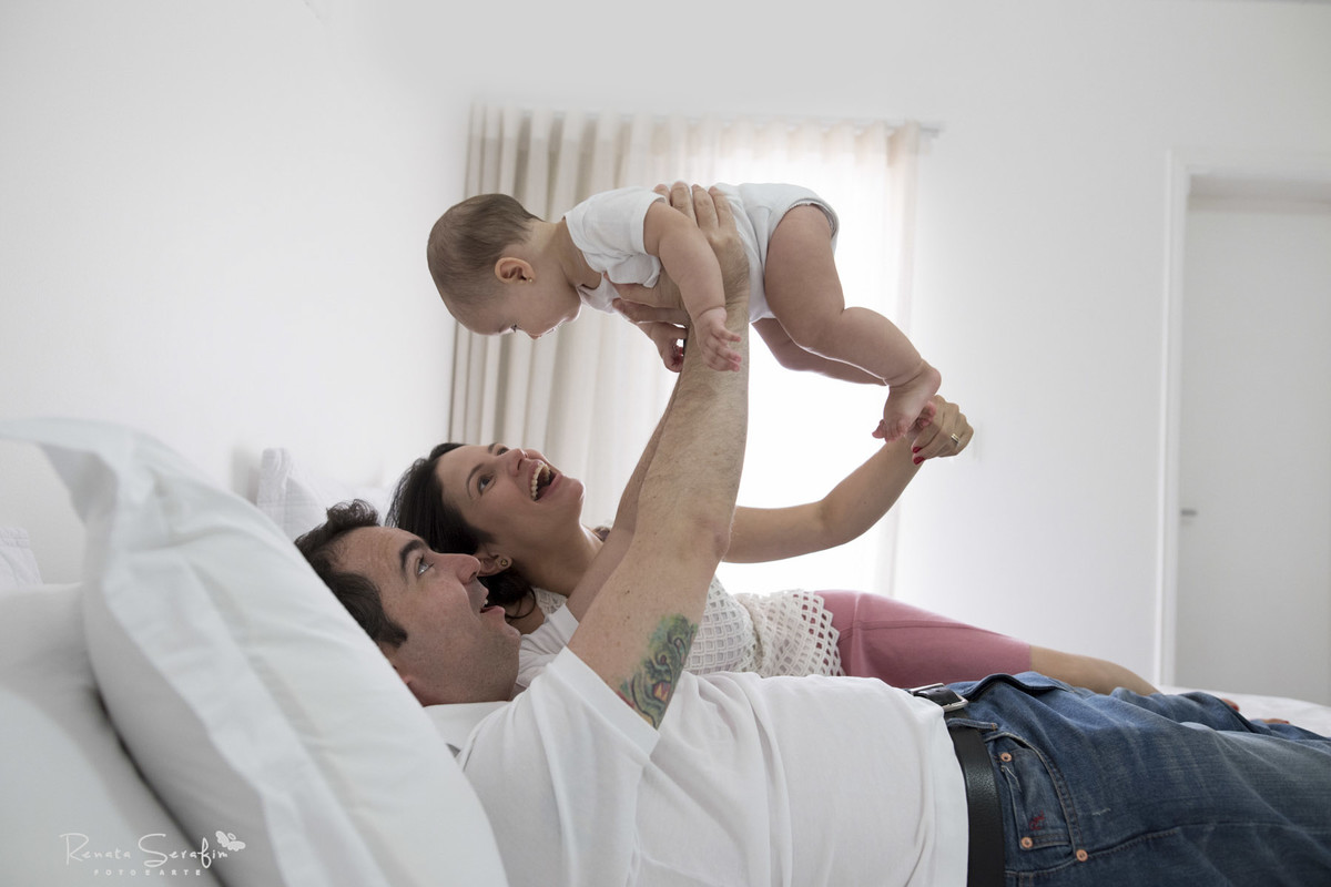 Papais brincando com sua filha, em sessão de fotos de bebê