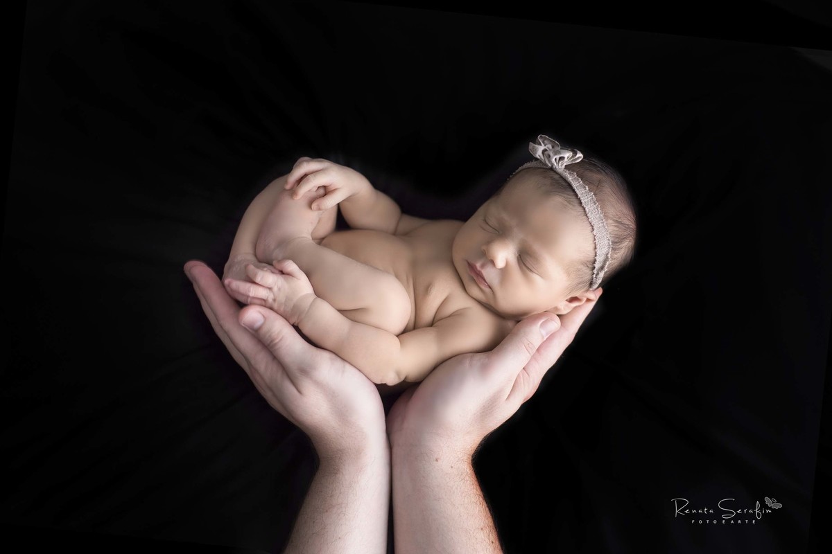 Maria clara segurada pelas mãos do seu pai no ensaio newborn