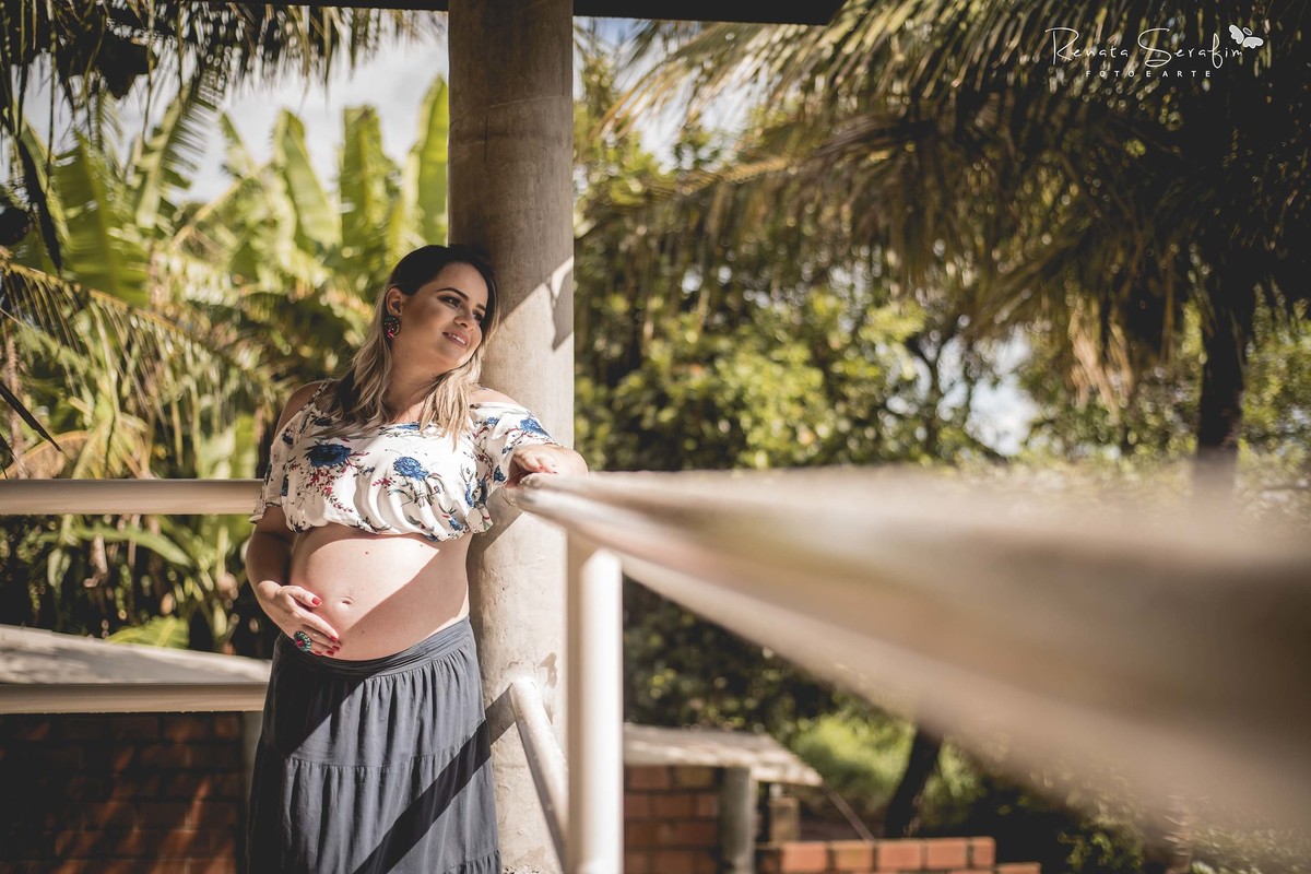 Linda mamae admirando a paisagem enquanto acariciava seu filho no ensaio fotográfico de gestante