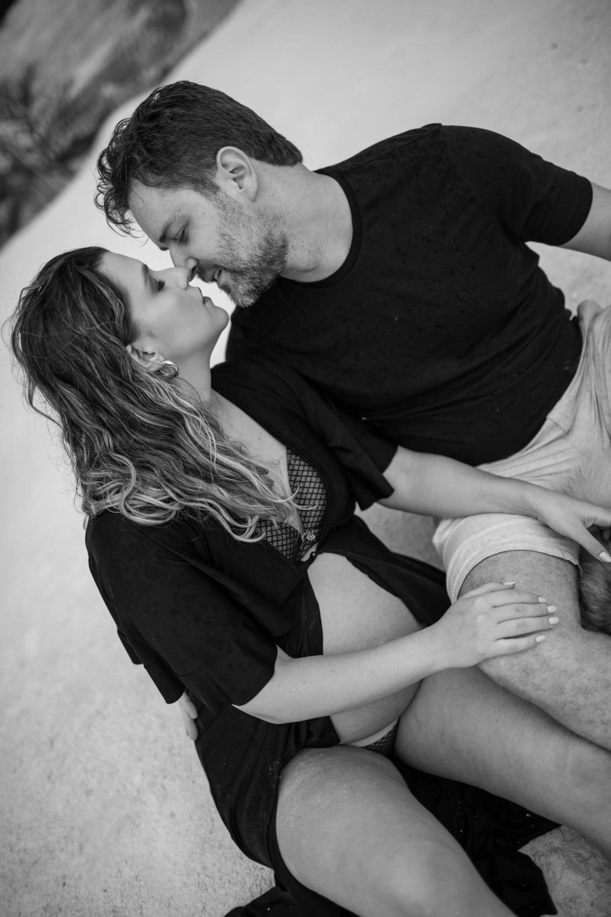 lose-up do casal sentado juntos, focando no rosto da gestante que sorri enquanto olha para o companheiro. A expressão de felicidade é destacada pela proximidade do casal. Fotos feitas pelo fotógrafo de gestante Rafael Ohana em Brasília.