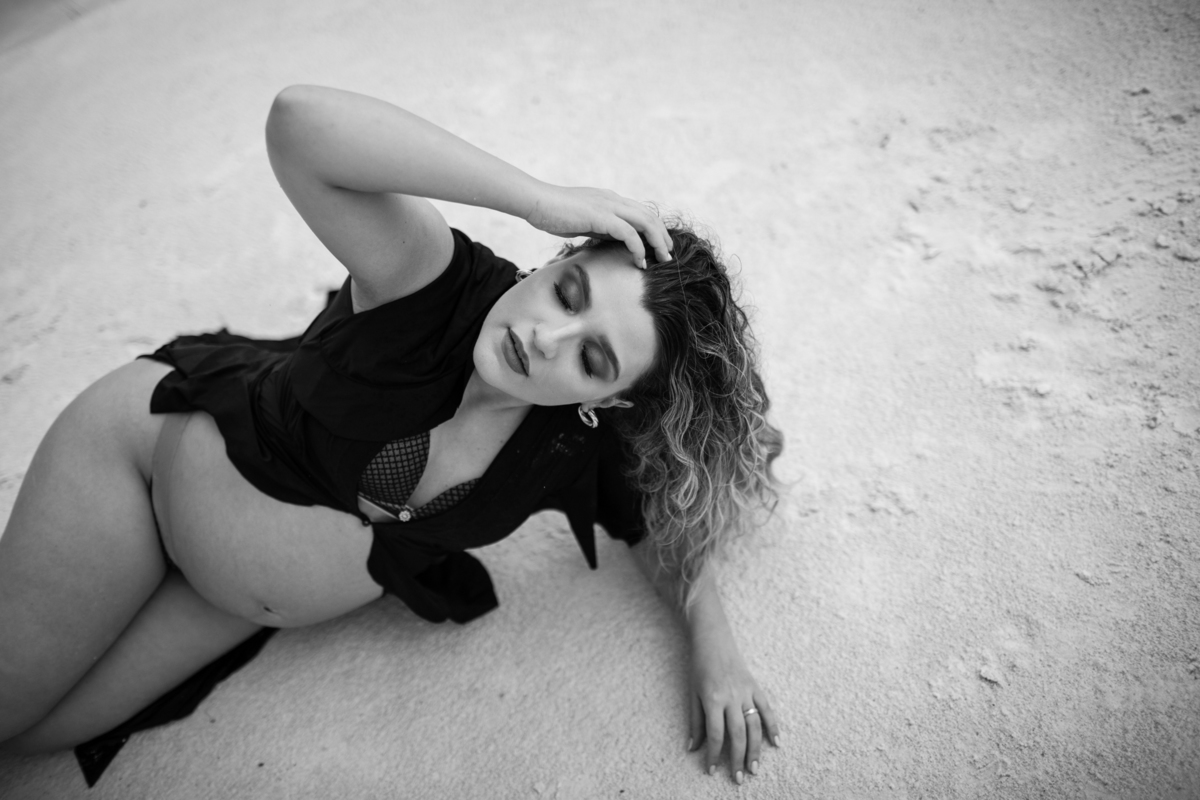 Outra imagem da gestante deitada, desta vez com um foco mais próximo. A pose e o olhar dela para a câmera evocam confiança e beleza. Fotos feitas pelo fotógrafo de gestante Rafael Ohana em Brasília.
