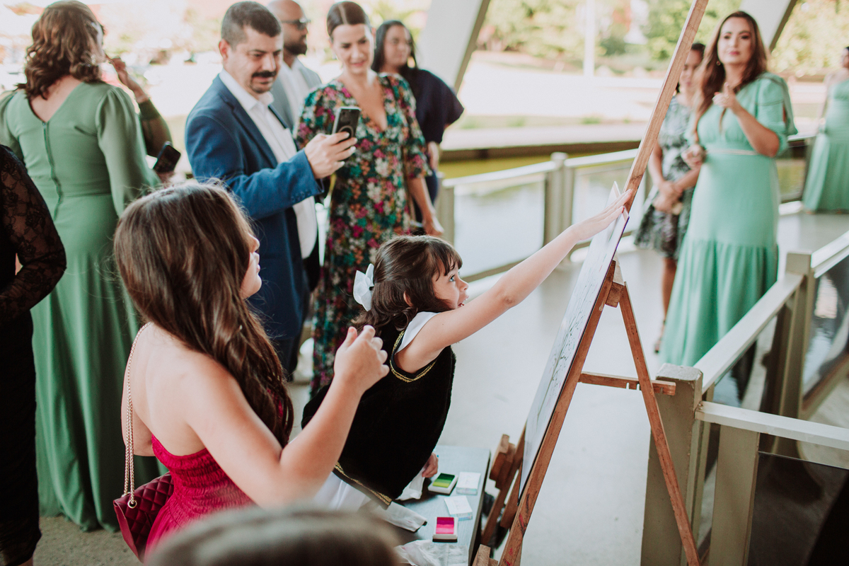 Menina colocando o dedo de tinta na árvore de convidados