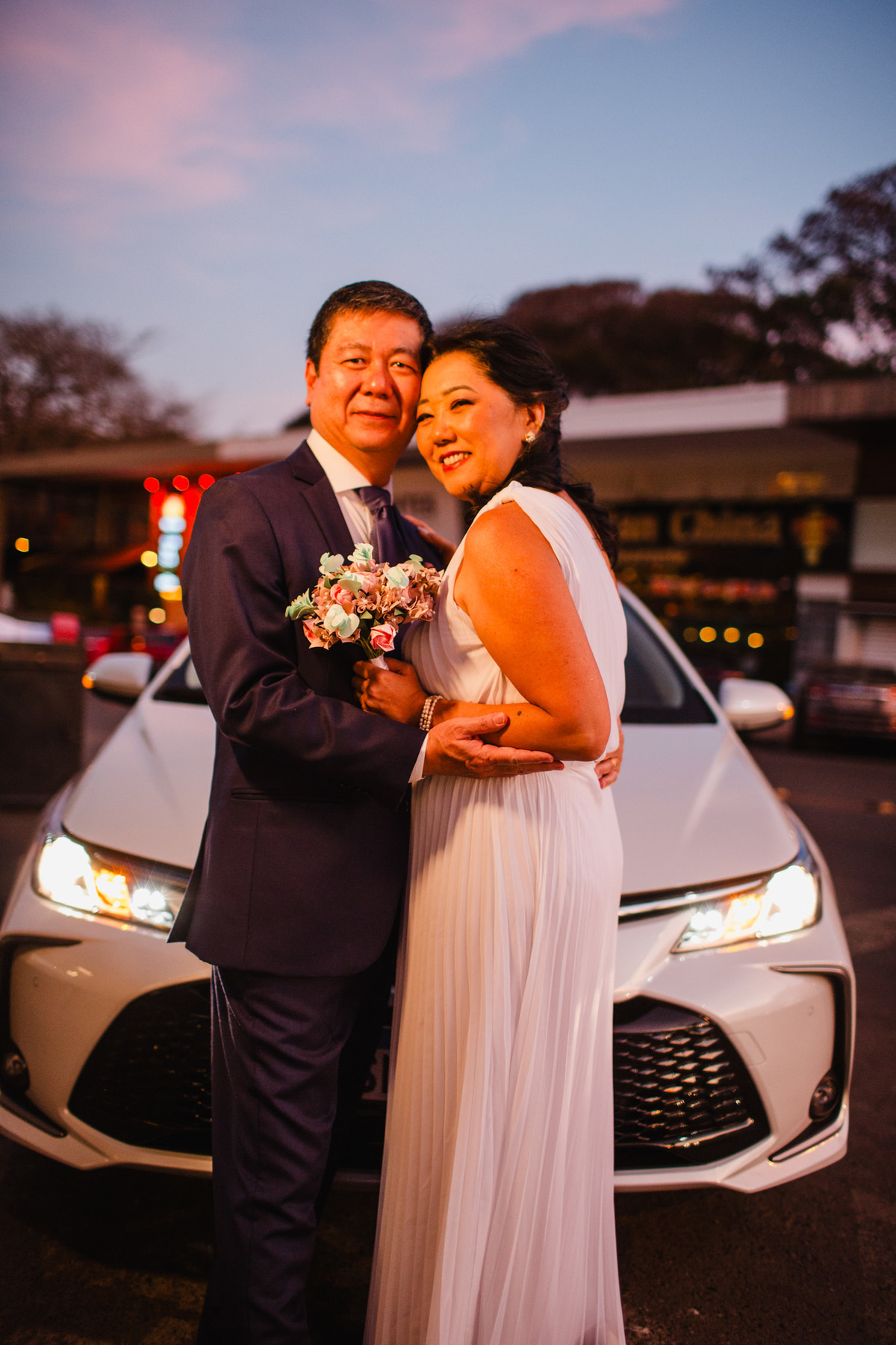 Casal japonês na frente de um carro japonses. Foto feita pelo fotógrafo de casamento Rafael Ohana em Brasília