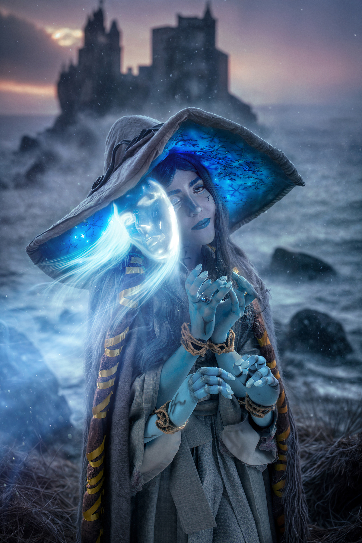 Cosplay de Ranni (Elden Ring). A figura feminina usa chapéu decorado, invocando uma presença mágica em um cenário preto e branco com castelo medieval ao fundo. Atmosfera de mistério e fantasia. Foto por Rafael Ohana em Brasília.