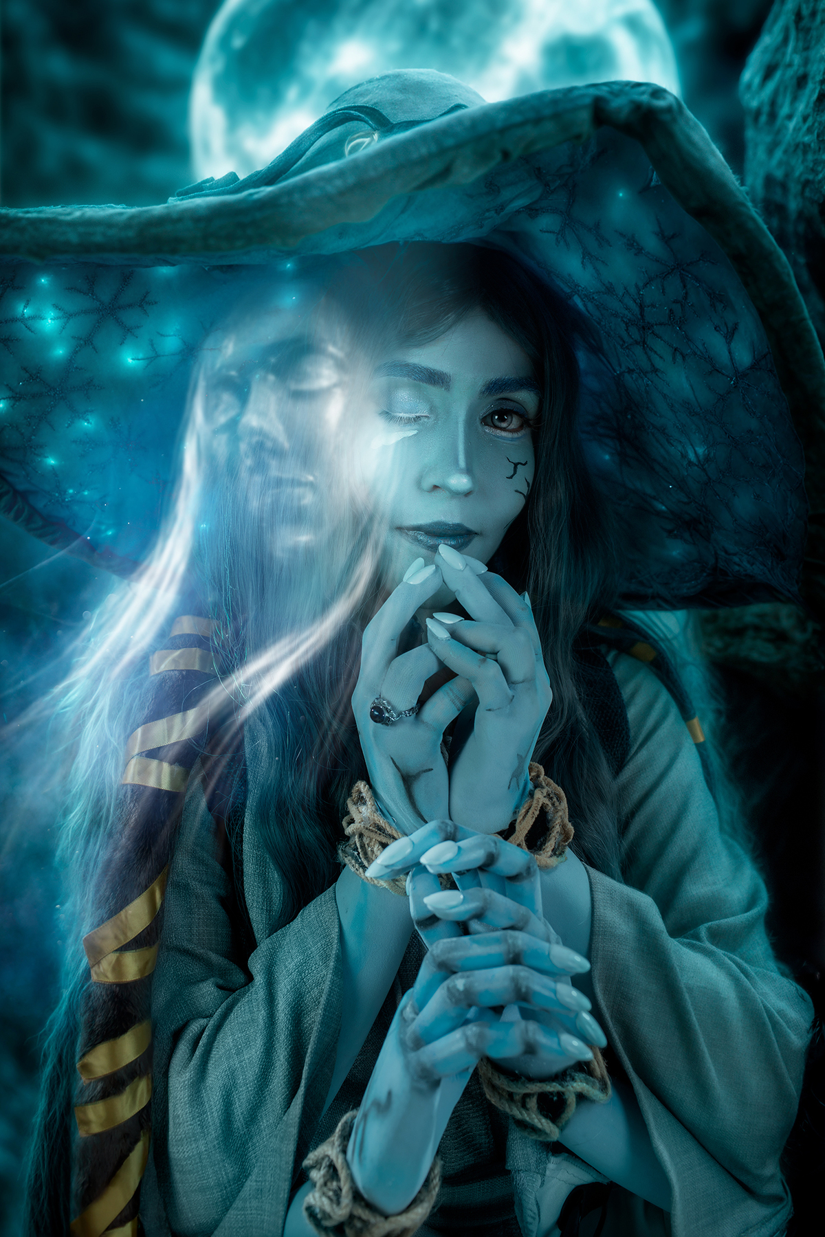Cosplay de Ranni (Elden Ring). Close-up de mulher azul com chapéu decorado, espírito guardião ao lado e lua cheia ao fundo, em atmosfera mística. Foto por Rafael Ohana em Brasília.