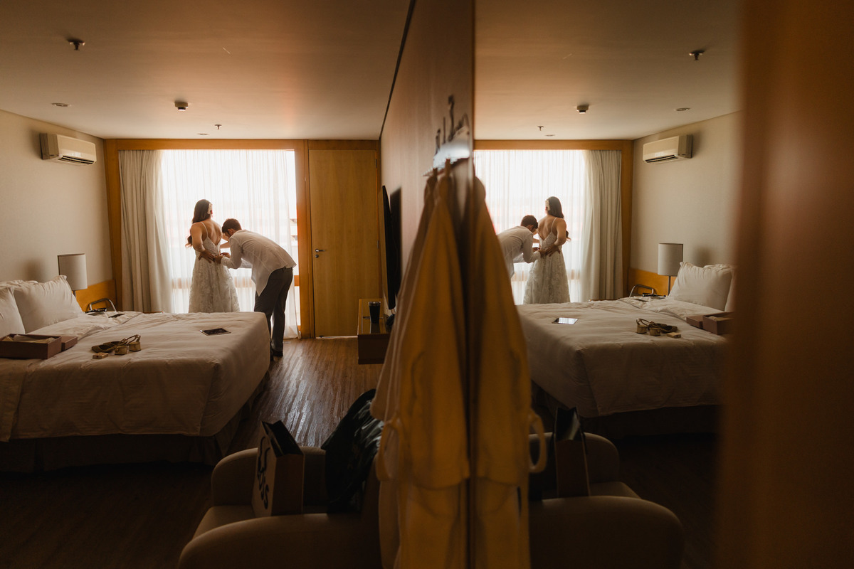 Noivo vestindo a noiva em making of de casamento. Foto feita no hotel Brasília Palace pelo fotógrafo Rafael Ohana