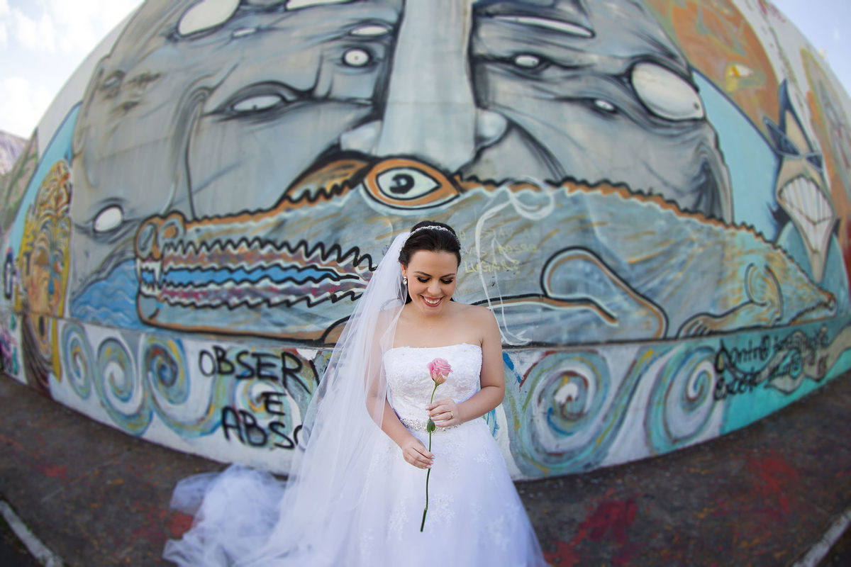 Noiva segurando rosa em frente a paredão grafitado no espaço Renato Russo em Brasília. Foto feita pelo fotógrafo de casamento Rafael Ohana