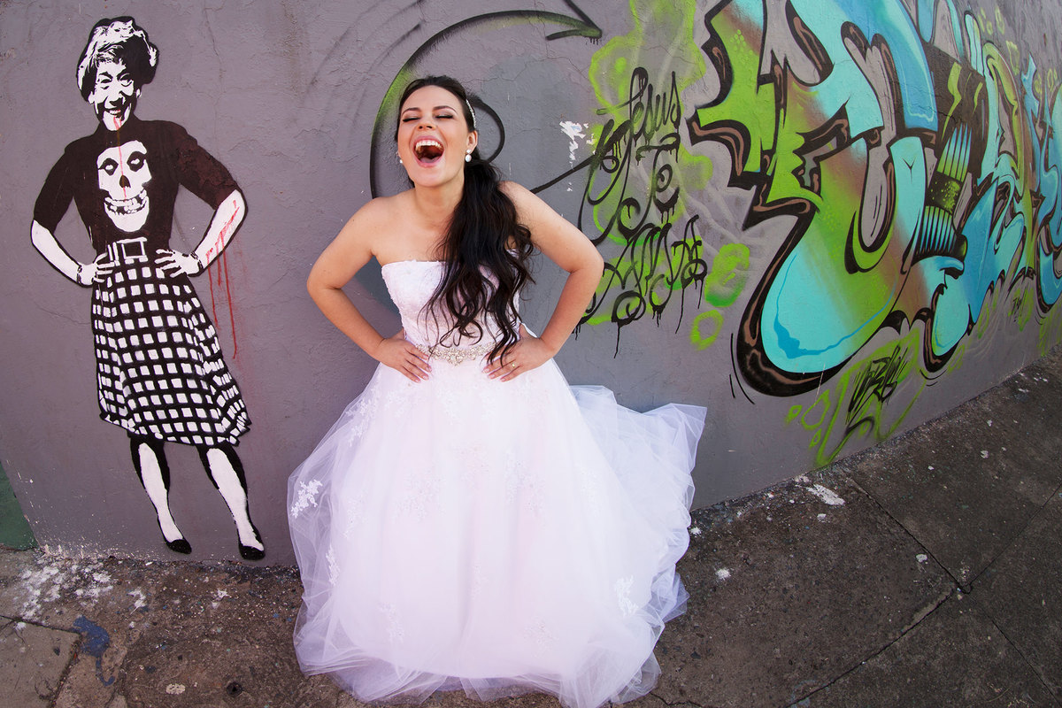 Noiva rindo perto de parede grafitada. Foto feita pelo fotógrafo de casamento Rafael Ohana 