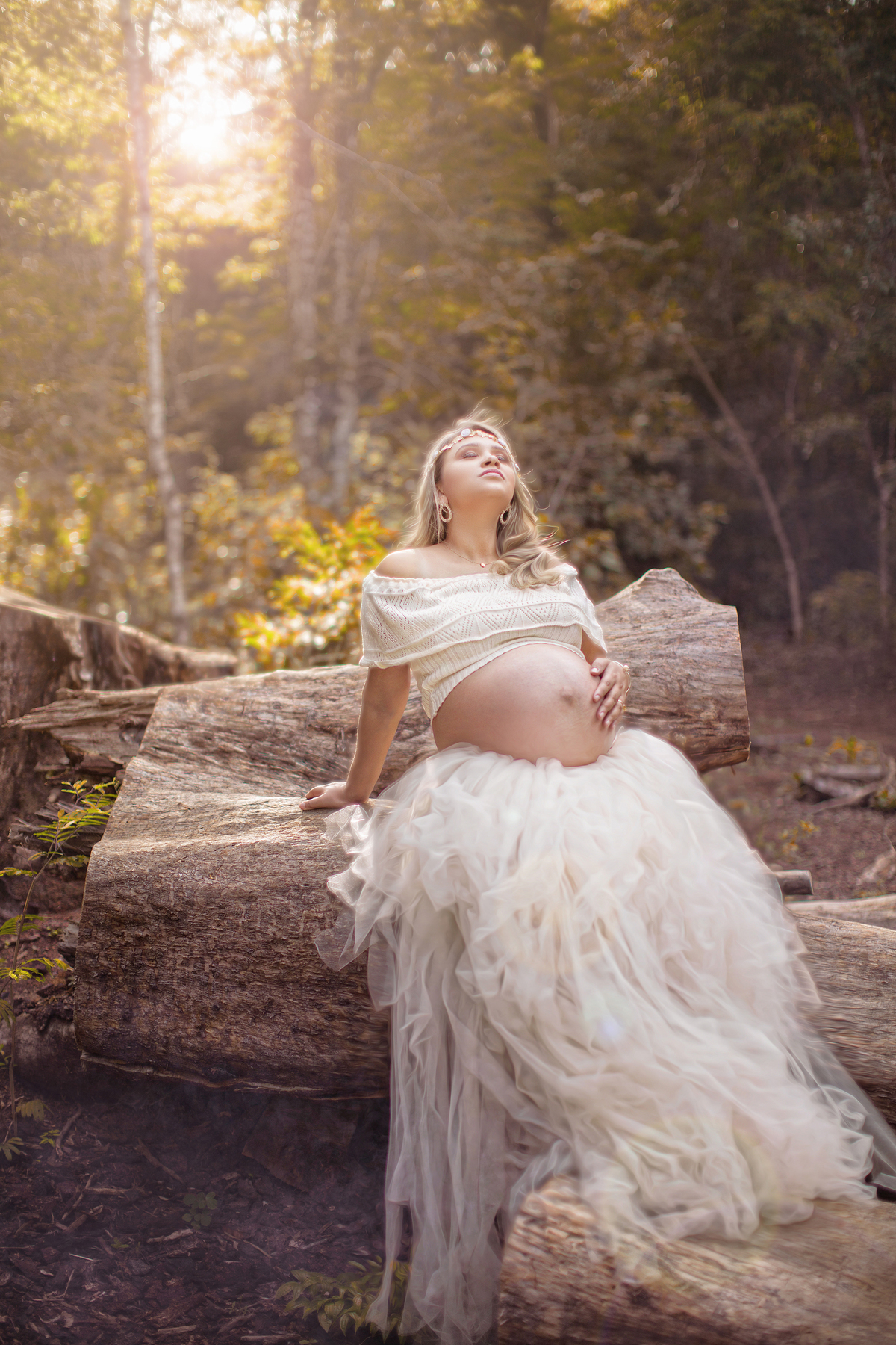 Grávida passando as mãos sobre a barriga encostada em troncos de arvore no parque olhos dagua. Fotofeita pelo fotógrafo Rafael Ohana fotógrafo de gestante em brasília. 