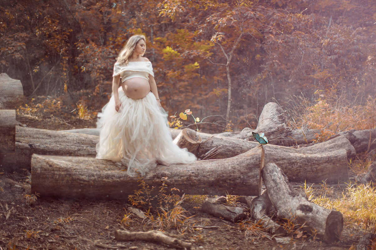 Grávida olhando para borboleta em cima de troncos de arvore no parque olhos dagua em Brasília-DF. Fotofeita pelo fotógrafo Rafael Ohana fotógrafo de gestante em brasília.