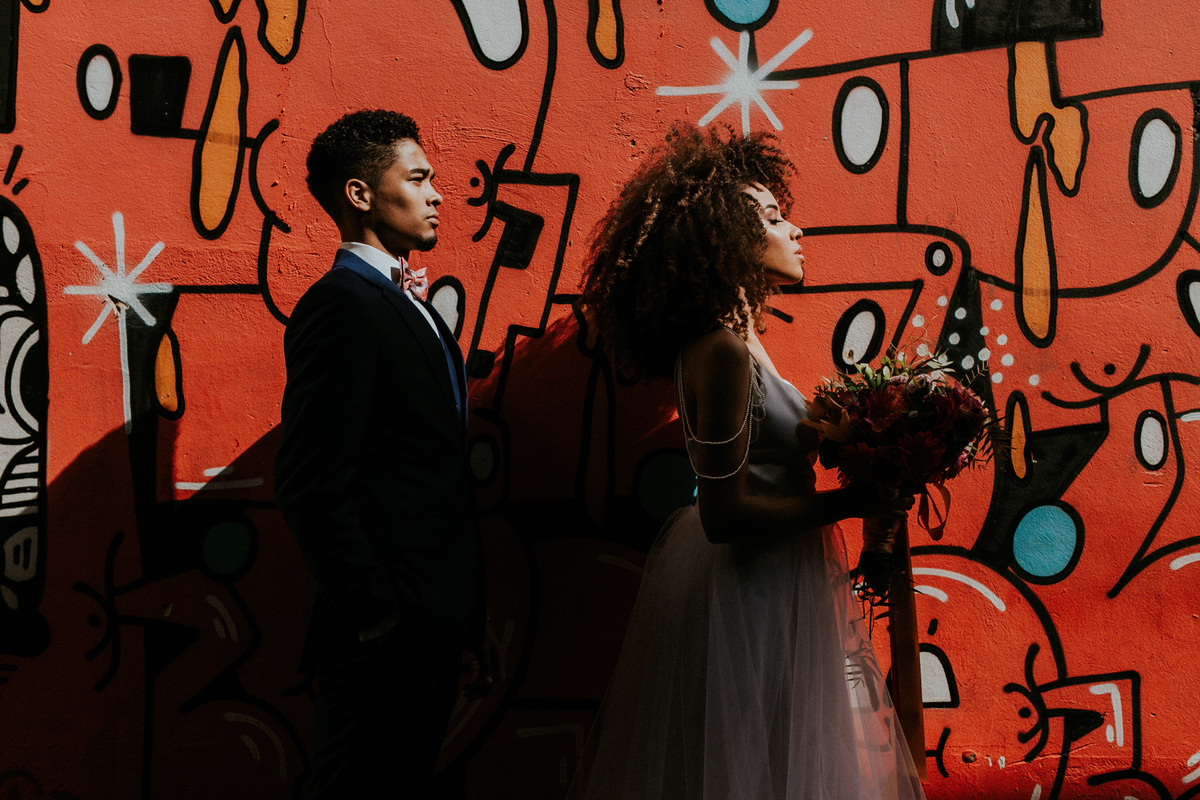 Casal de noivos negros posando em parede de grafitti no Dulcina em Brasilia. Foto feita pelo fotografo de bodas Rafael Ohana em Brasilia