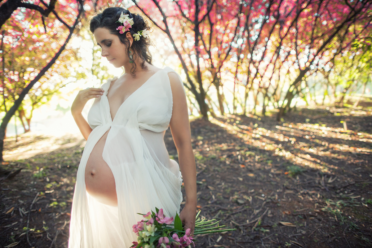 Grávida maravilhosa com flores no bosque rosa. Ensaio fotográfico feito pelo fotógrafo de gestante Rafael Ohana no parque olhos d´água em Brasília-DF