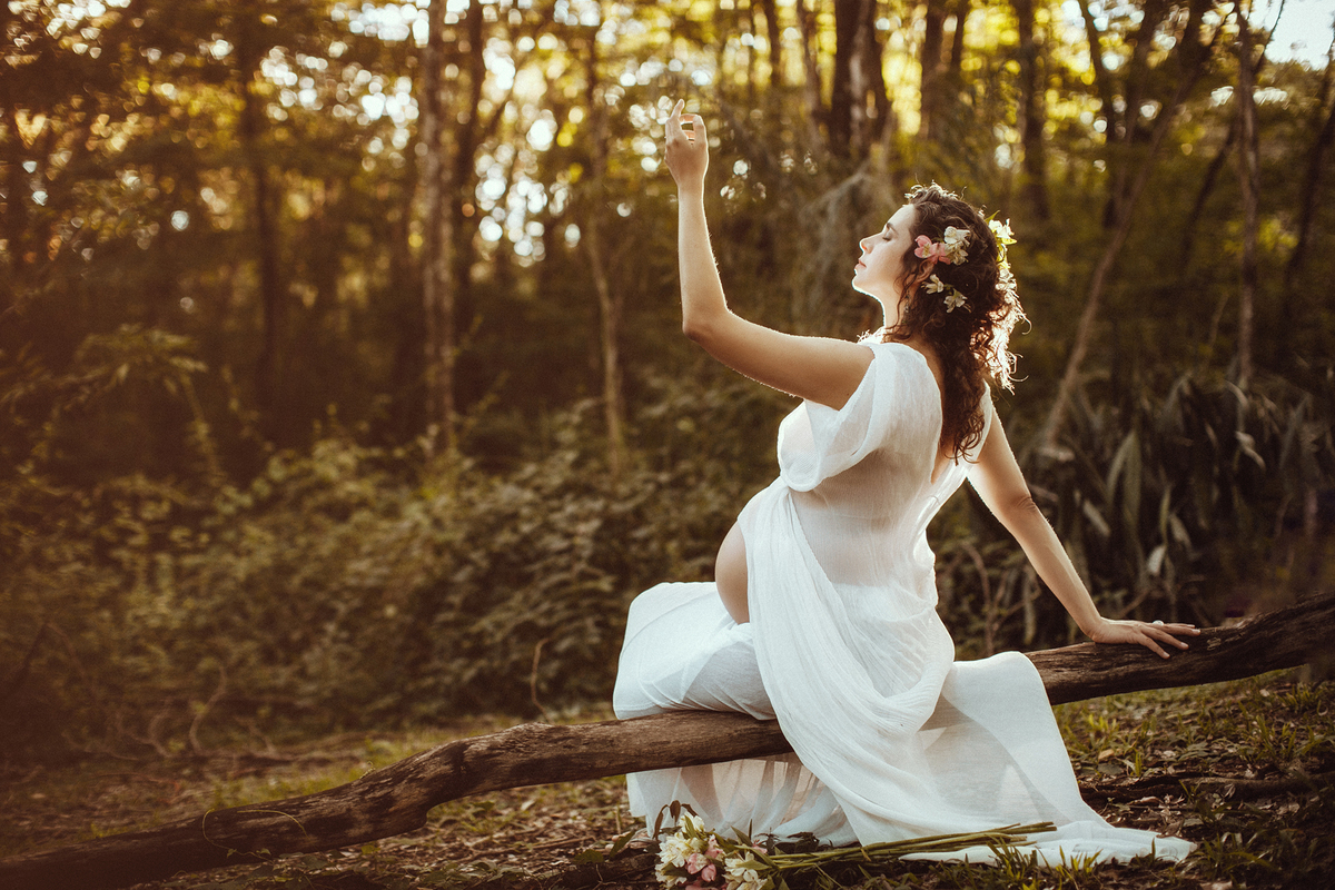 Grávida dançando sozinha na floresta. Ensaio fotográfico feito pelo fotógrafo de gestante Rafael Ohana no parque olhos d´água em Brasília-DF
