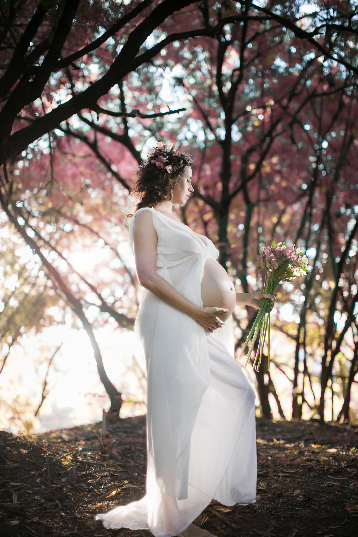 Grávida colhendo flores no bosque. Ensaio fotográfico feito pelo fotógrafo de gestante Rafael Ohana no parque olhos d´água em Brasília-DF