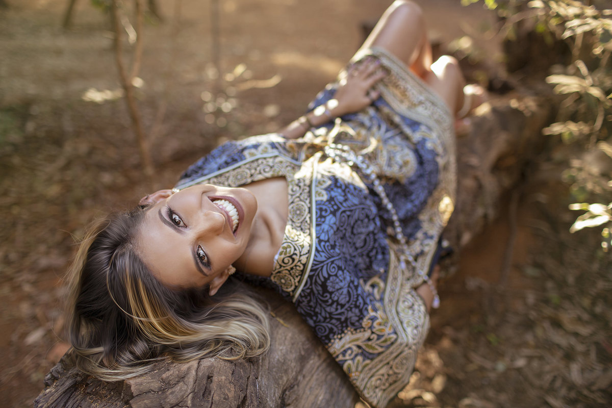 Mulher deitada sorrindo. Ensaio feminino feito pelo fotógrafo Rafael Ohana no Parque Olhos D´água em Brasília-DF 