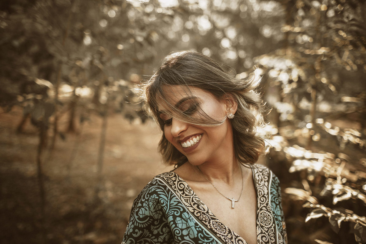 Mulher sorrindo na floresta. Ensaio feminino feito pelo fotógrafo Rafael Ohana no Parque Olhos D´água em Brasília-DF 