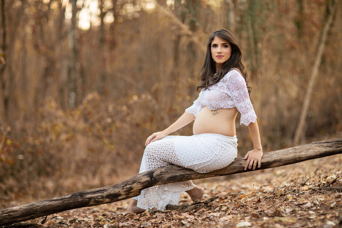 Gestante sentada em tronco de arvore na floresta. Foto feita pelo fotógrafo Rafael Ohana no parque Olhos D´água em Brasília-DF.