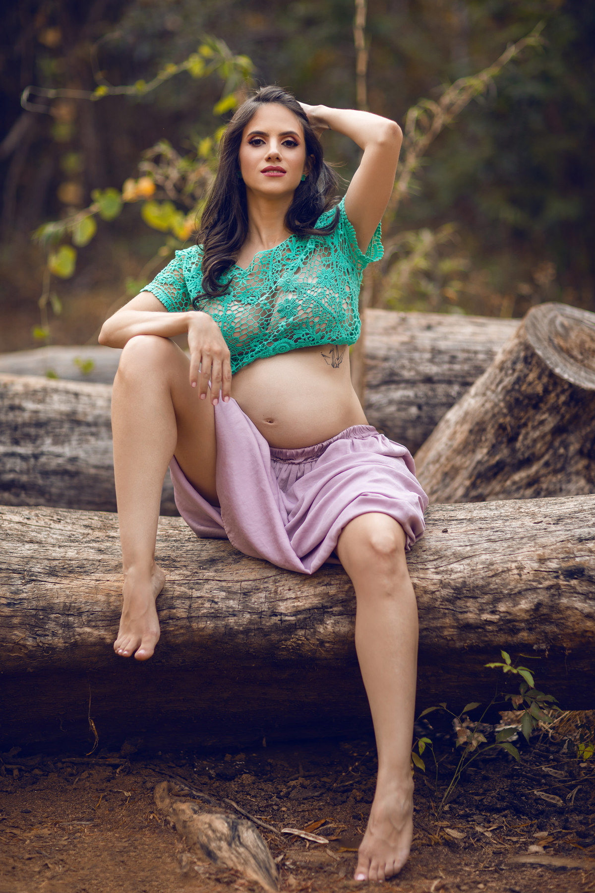 Grávida posando sentada em tronco de árvore. Foto feita pelo fotógrafo Rafael Ohana no parque Olhos D´água em Brasília-DF.