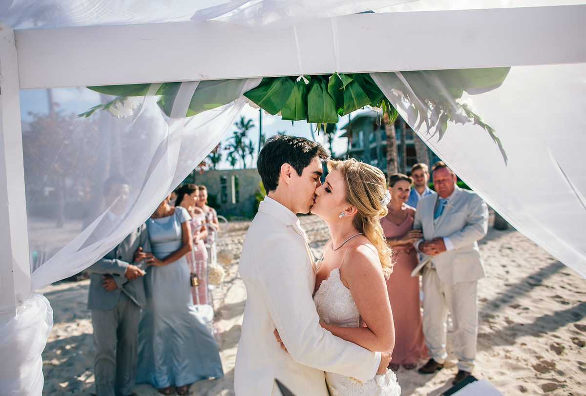 Beijo dos noivos na praia. Casamento realizado no resort Barceló Bávaro Palace na República Dominicana pelo fotógrafo de casamento Rafael Ohana