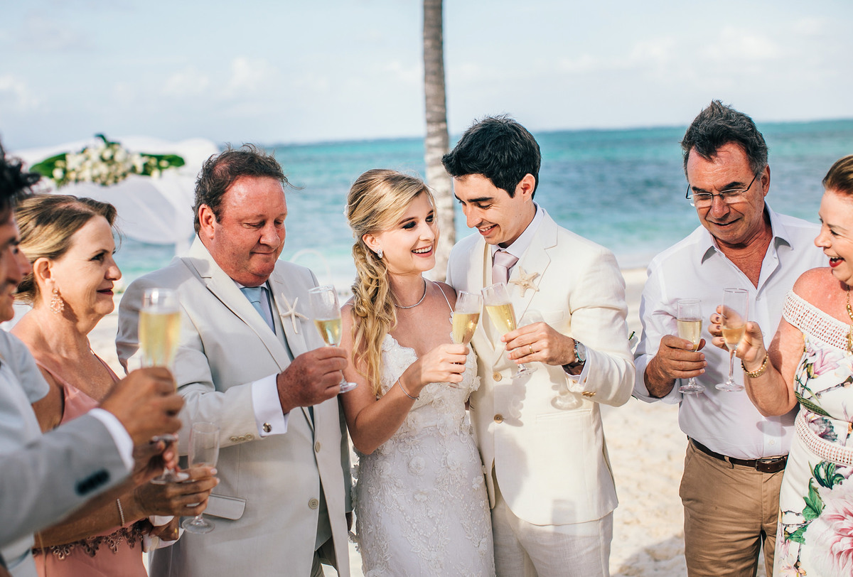 Noivos brindando com convidados. Casamento realizado no resort Barceló Bávaro Palace na República Dominicana pelo fotógrafo de casamento Rafael Ohana