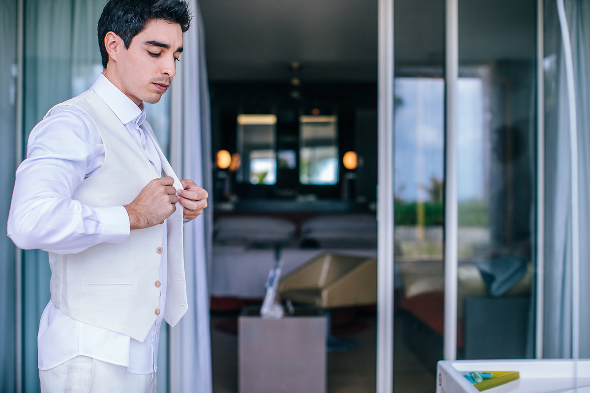 Noivo se vestindo para seu casamento a praia. Casamento realizado no resort Barceló Bávaro Palace na República Dominicana pelo fotógrafo de casamento Rafael Ohana