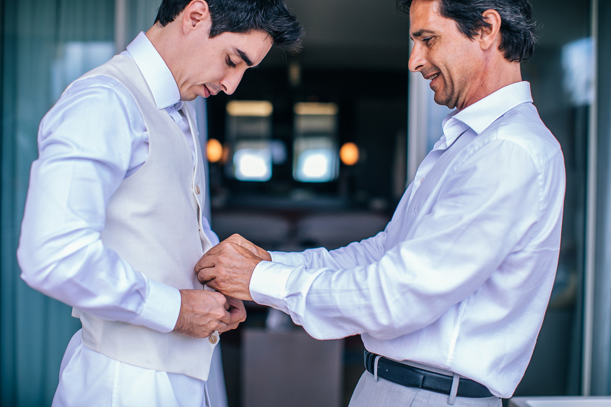 Pai do noivo ajudando noivo a se arrumar. Casamento realizado no resort Barceló Bávaro Palace na República Dominicana pelo fotógrafo de casamento Rafael Ohana