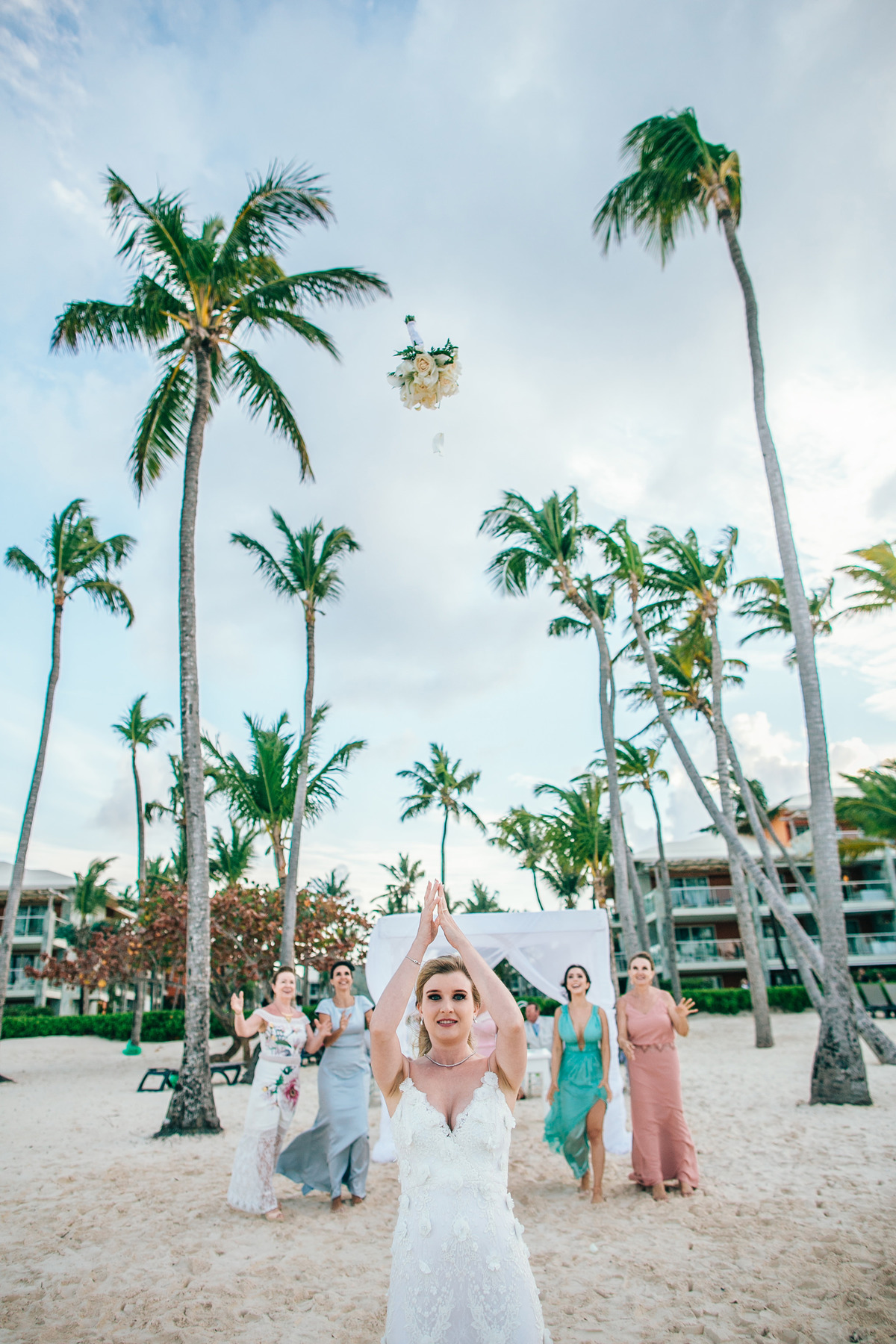 Noiva jogando buquê na praia. Casamento de praia realizado no resort Barceló Bávaro Palace na República Dominicana pelo fotógrafo de casamento Rafael Ohana