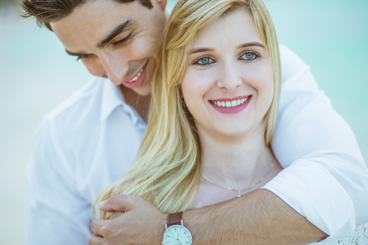 Noivo abraçando noiva por trás. Ensaio de romântico na praia realizado no resort Barceló Bávaro Palace na República Dominicana pelo fotógrafo de casamento Rafael Ohana