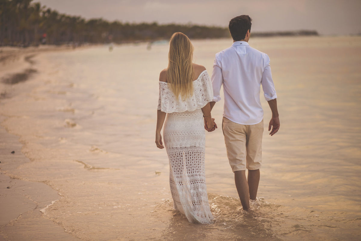 Noivos caminhando na praia no final do dia. 