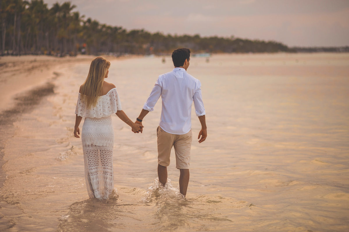 Noivos caminhando ao por do sol. Ensaio de romântico na praia realizado no resort Barceló Bávaro Palace na República Dominicana pelo fotógrafo de casamento Rafael Ohana