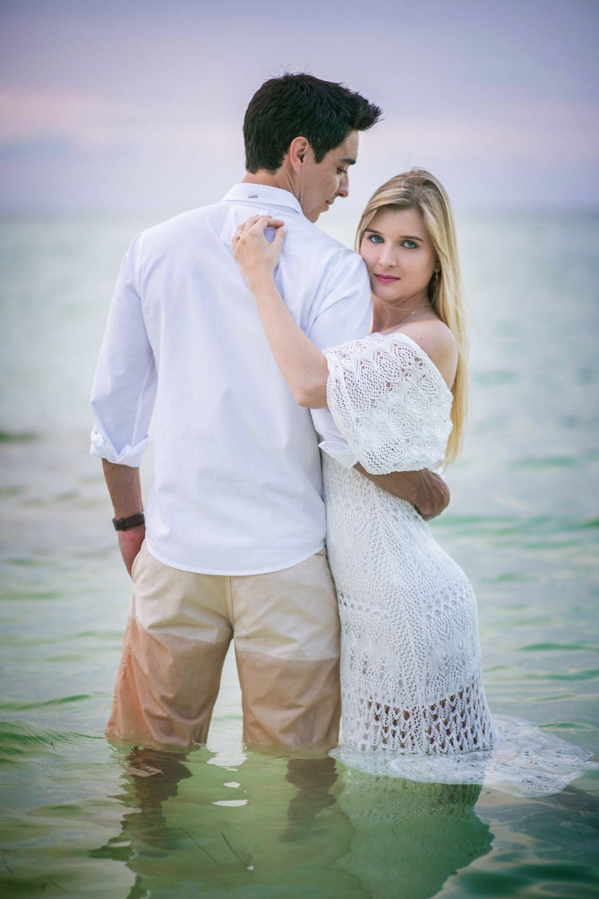 Noivos na praia de água azul. Ensaio de romântico na praia realizado no resort Barceló Bávaro Palace na República Dominicana pelo fotógrafo de casamento Rafael Ohana