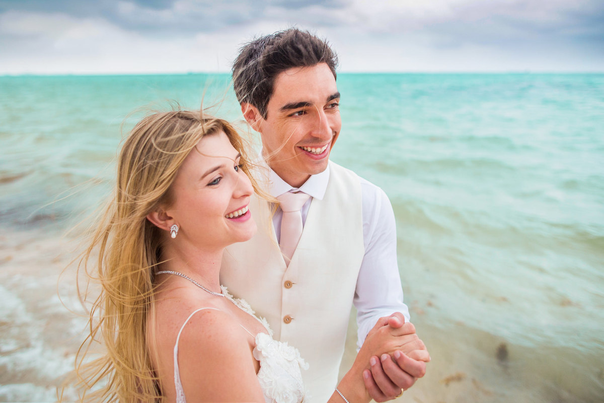 Noivos rindo na praia. Ensaio day after na praia realizado no resort Barceló Bávaro Palace na República Dominicana pelo fotógrafo de casamento Rafael Ohana