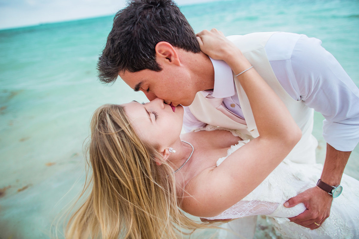 Noivos se beijando na praia. Ensaio day after na praia realizado no resort Barceló Bávaro Palace na República Dominicana pelo fotógrafo de casamento Rafael Ohana