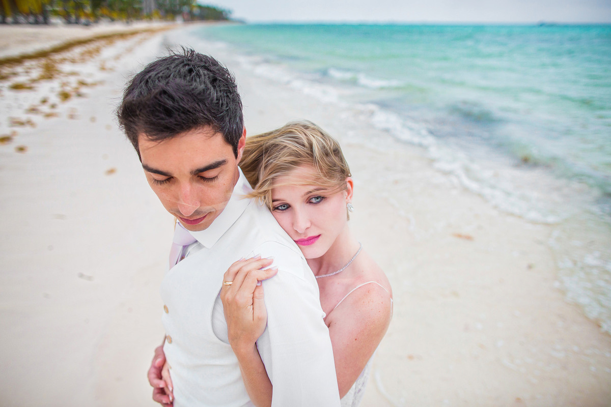 Noiva abraçando noivo por trás. Ensaio day after na praia realizado no resort Barceló Bávaro Palace na República Dominicana pelo fotógrafo de casamento Rafael Ohana