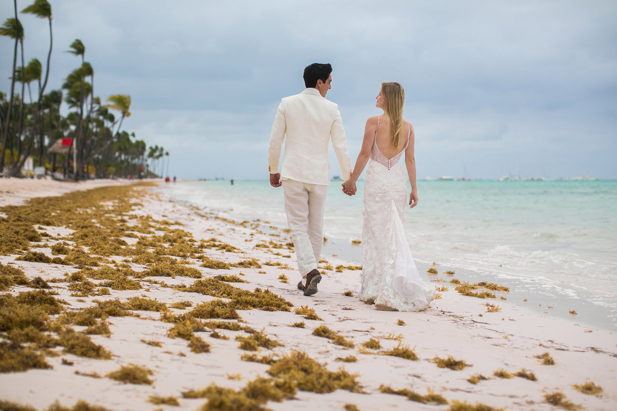 Noivos caminhando na praia. Ensaio day after na praia realizado no resort Barceló Bávaro Palace na República Dominicana pelo fotógrafo de casamento Rafael Ohana