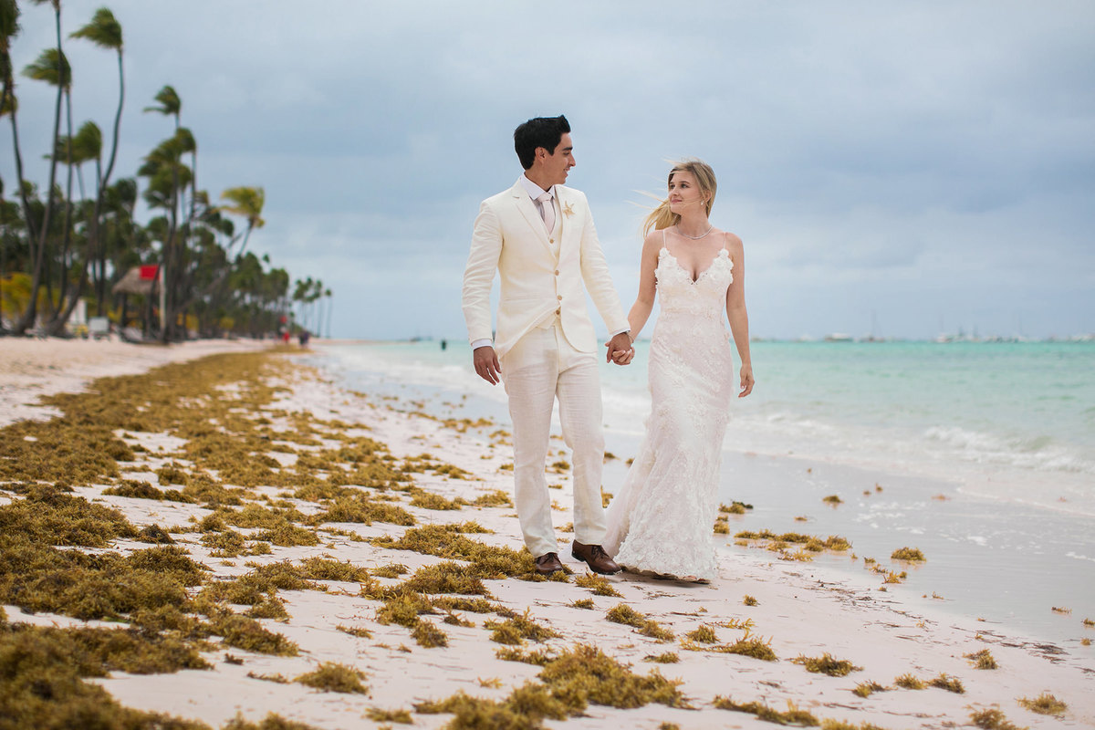 Noivos caminhando na praia. Ensaio day after na praia realizado no resort Barceló Bávaro Palace na República Dominicana pelo fotógrafo de casamento Rafael Ohana