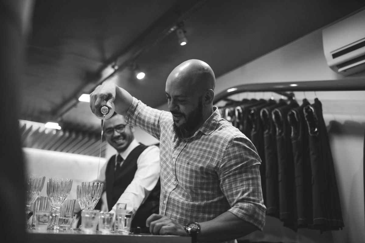 Noivo servindo bebida pros padrinhos em Alfaiataria Camargo. Foto feita pelo fotógrafo de casamento Rafael Ohana em Brasília-DF.