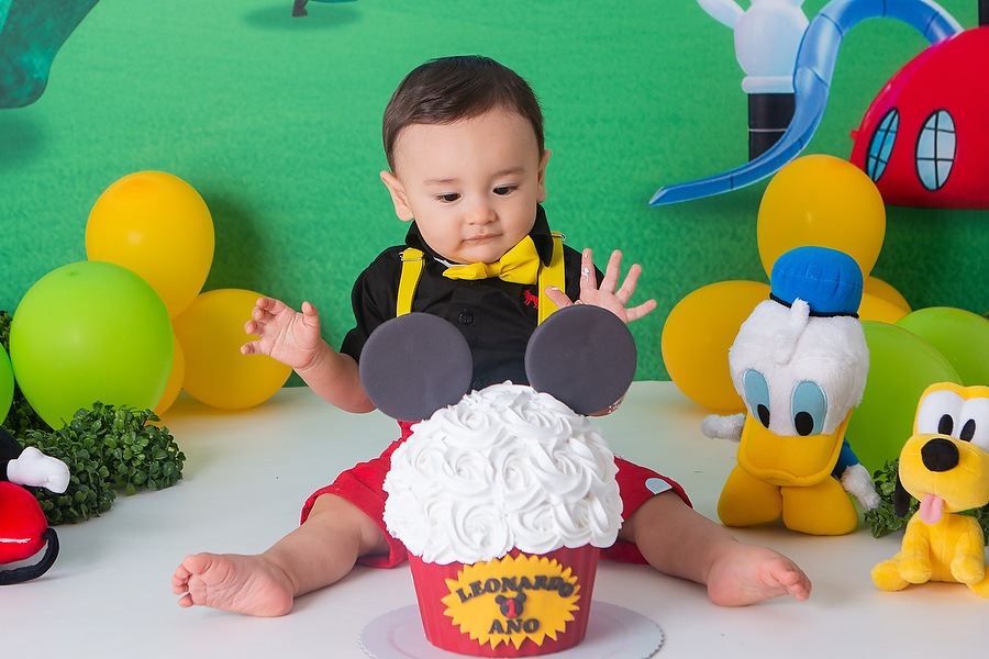ensaio smash the cake, com tema a casa do mickey mouse, com bolo temático, festa diferente para comemorar 1 ano, festa de 1 ano, esmagando o bolo. 