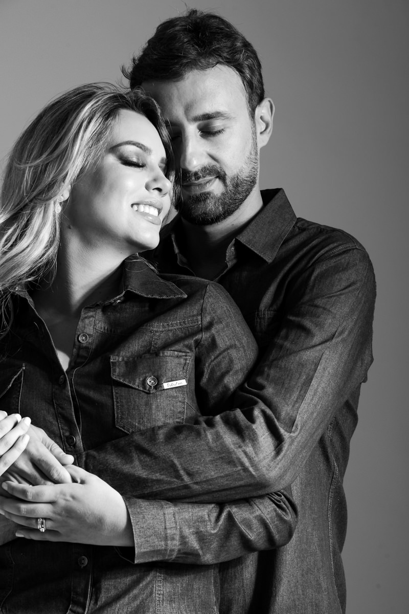 Ensaio de pre wedding em estúdio do lindo casal Mariane e Eduardo, fotografado pelo fotógrafo de ensaios e casamento em Campo Largo e Curitiba, Michel Druziki. Noivos de jeans abraçados e sorrindo de olhos fechados