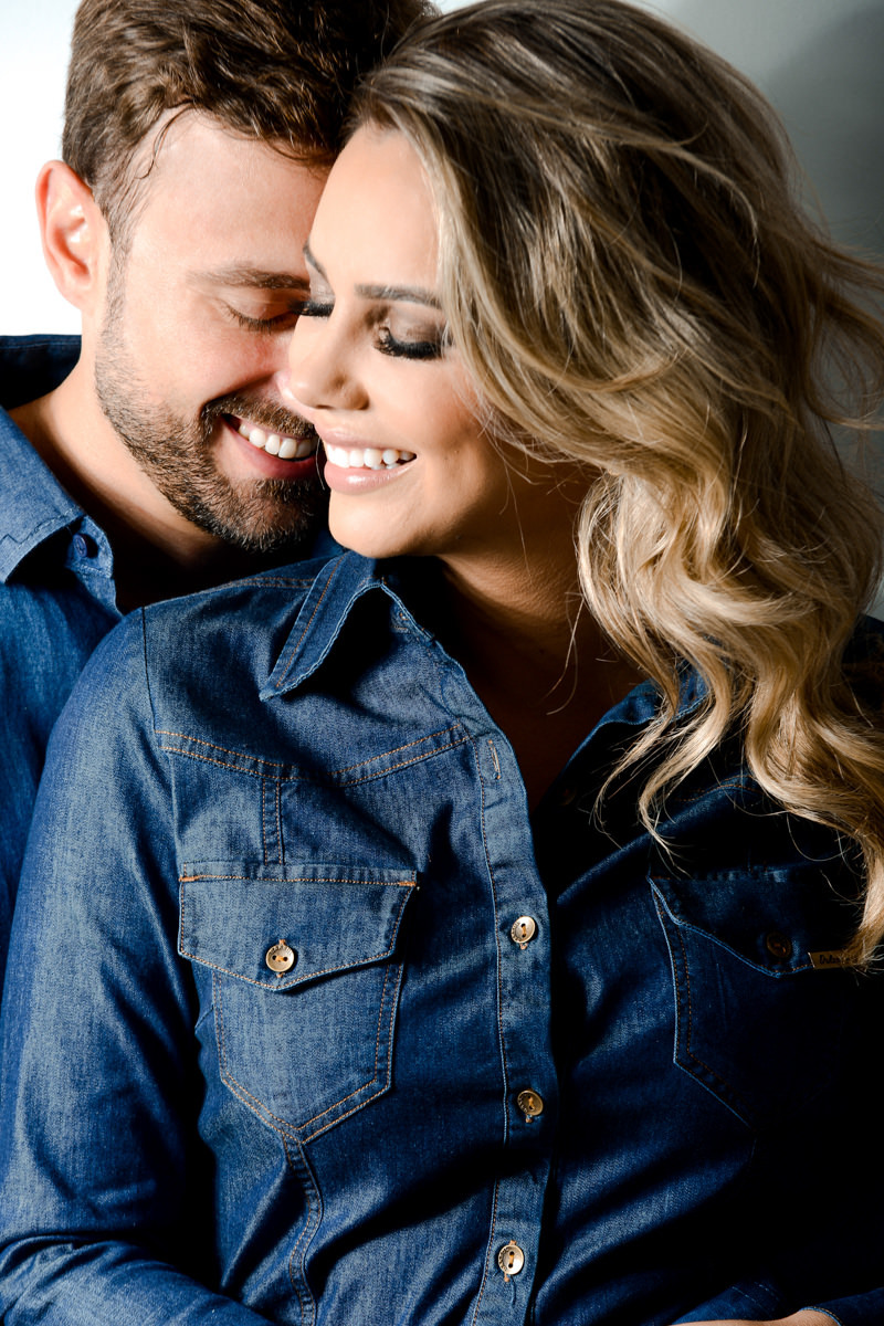 Ensaio de pre wedding em estúdio do lindo casal Mariane e Eduardo, fotografado pelo fotógrafo de ensaios e casamento em Campo Largo e Curitiba, Michel Druziki. Noivos de jeans abraçados e sorrindo e de olhos fechados