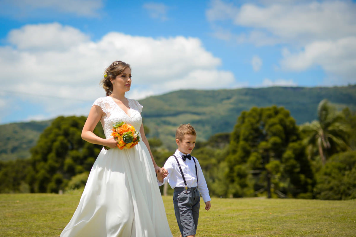 Casamento dos noivos Anna e Bruno ao ar livre em um dia lindo, na região de Curitiba e Campo Largo, fotografado pelo fotógrafo de casamentos Michel Druziki. Entrada da noiva acompanhada do filho