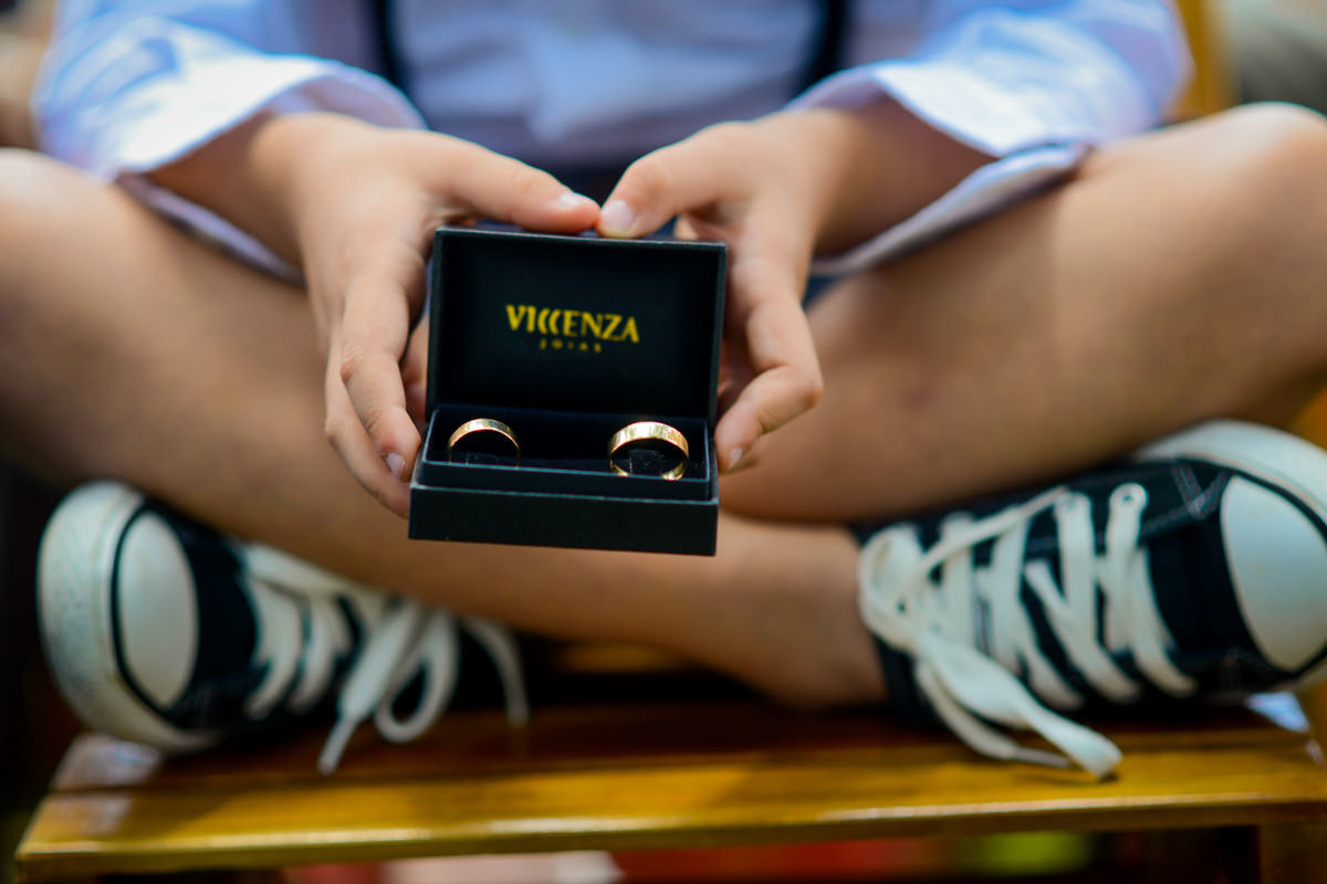 Casamento dos noivos Anna e Bruno ao ar livre em um dia lindo, na região de Curitiba e Campo Largo, fotografado pelo fotógrafo de casamentos Michel Druziki. Pagem de all star segurando as alianças 
