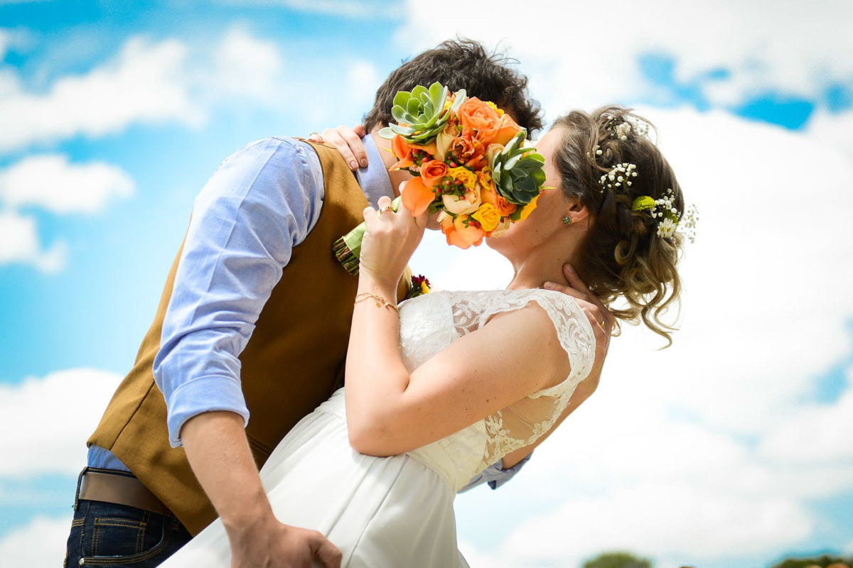 Casamento dos noivos Anna e Bruno ao ar livre em um dia lindo, na região de Curitiba e Campo Largo, fotografado pelo fotógrafo de casamentos Michel Druziki. Noiva escondendo o beijo com o buquê